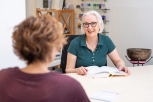 Antje Hansen in ihrer Naturheilpraxis in Forchheim am Schreibtisch mit Laptop und Klangschale – Expertin für Kinesiologie und Brain Gym®