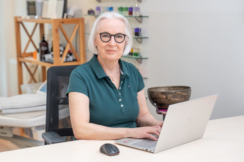 Antje Hansen in ihrer Naturheilpraxis in Forchheim am Schreibtisch mit Laptop und Klangschale – Expertin für Kinesiologie und Brain Gym®